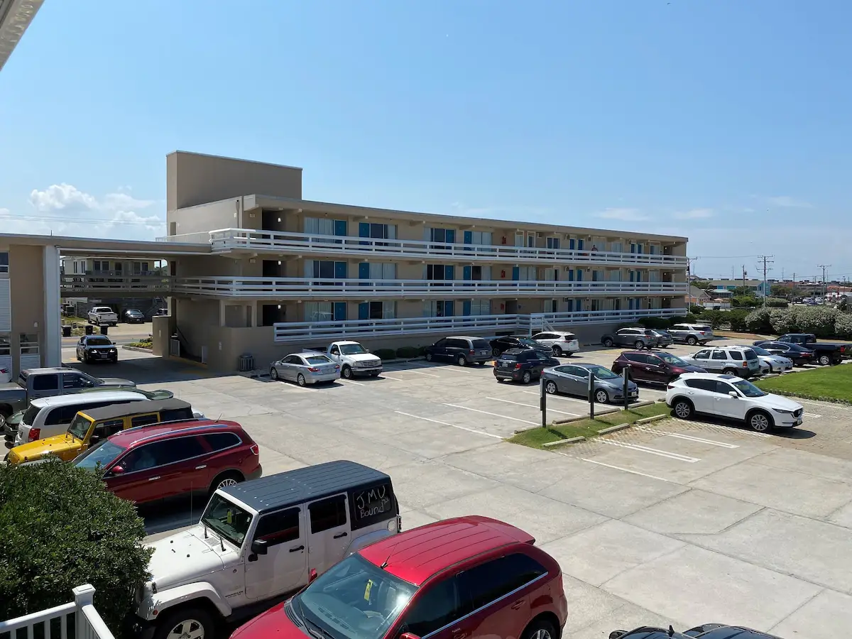 Mariner Inn & Suites, a three-storey building with white balcony railings and blue doors, seen from the parking lot with cars parked below