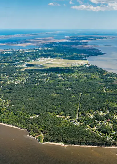 An aerial view of Roanoke Island and the surrounding sound, with forest, an airstrip and the coastline visible